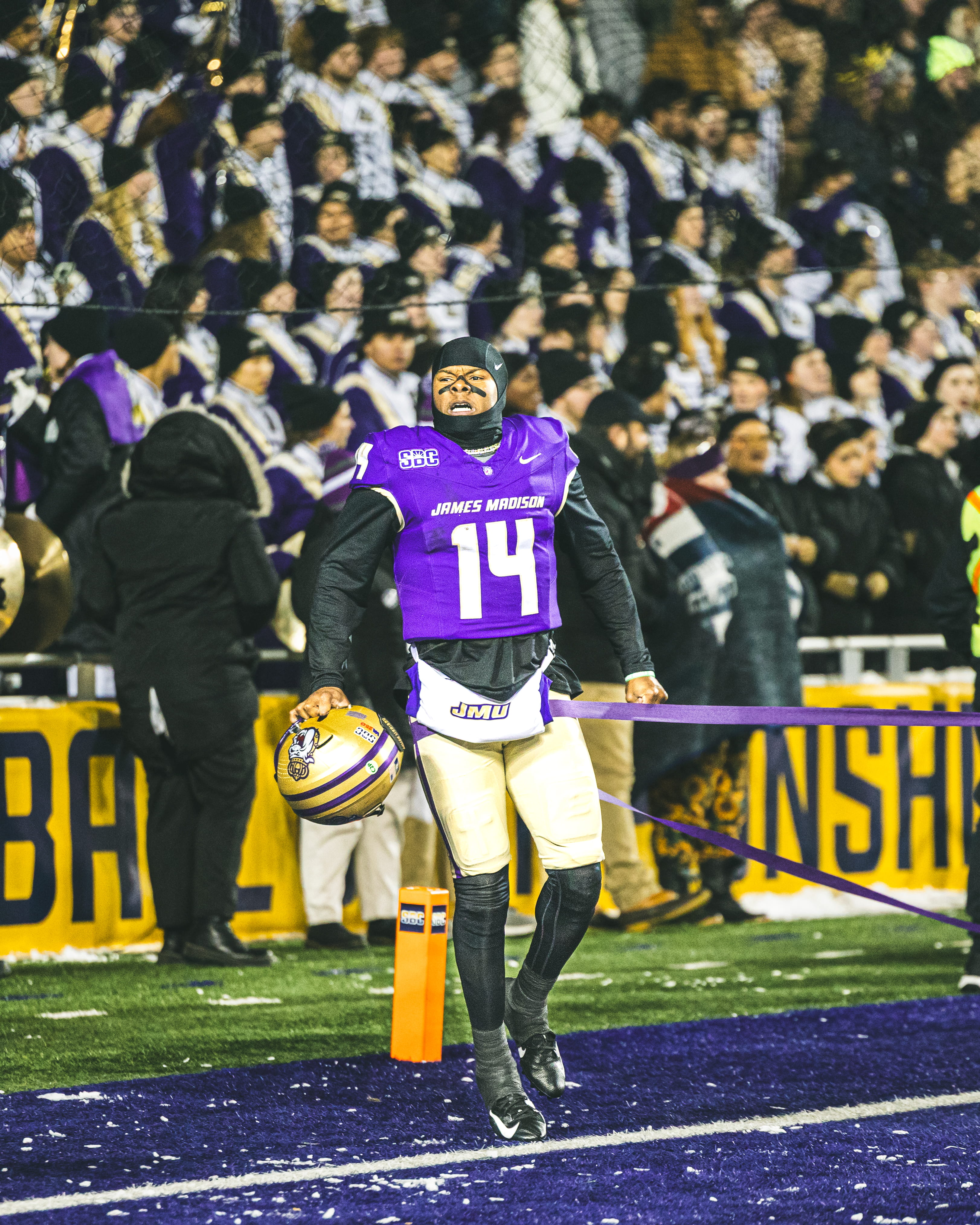 JMU football player holding his helmet after a touchdown